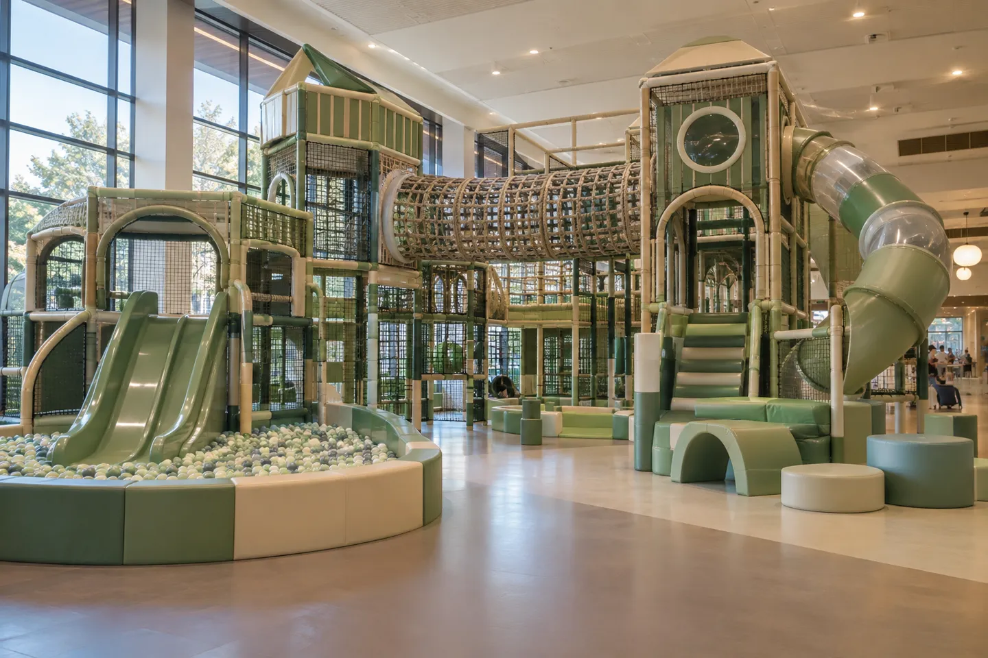 Wide view of a modern indoor playground structure with slides, a ball pit and climbing nets — the equipment an indoor playground maintenance program has to keep safe every day